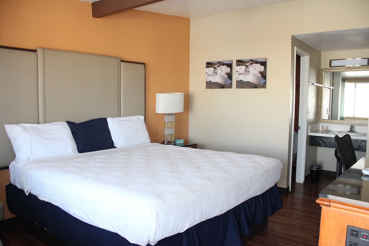 Una habitación de hotel con una cama grande, un escritorio y un espejo.