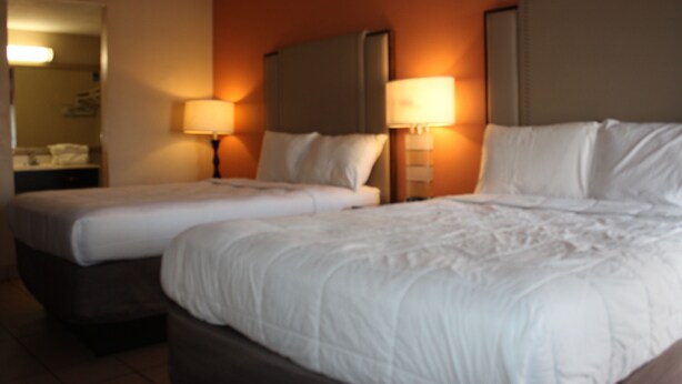 Une chambre d’hôtel avec deux lits, chacun doté d’une tête de lit et de lampes de chevet.