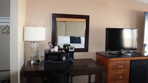 Une chambre d’hôtel équipée d’un bureau, d’une télévision, d’un miroir et d’un lit.