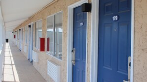 Une rangée de chambres d’hôtel aux portes bleues, numérotées 178 et 179, le long d’un couloir doté de fenêtres et d’ouvertures de ventilation.
