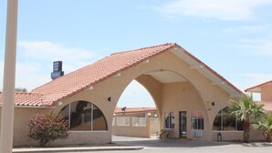 Un bâtiment doté d’un toit recouvert de tuiles rouges, d’une entrée en arc de cercle et d’une enseigne indiquant le mot « Connaissance ».