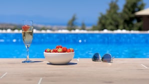 Klarer Blick auf einen Pool mit Holzterrasse, einem Glas Champagner und einer Schale Erdbeeren.