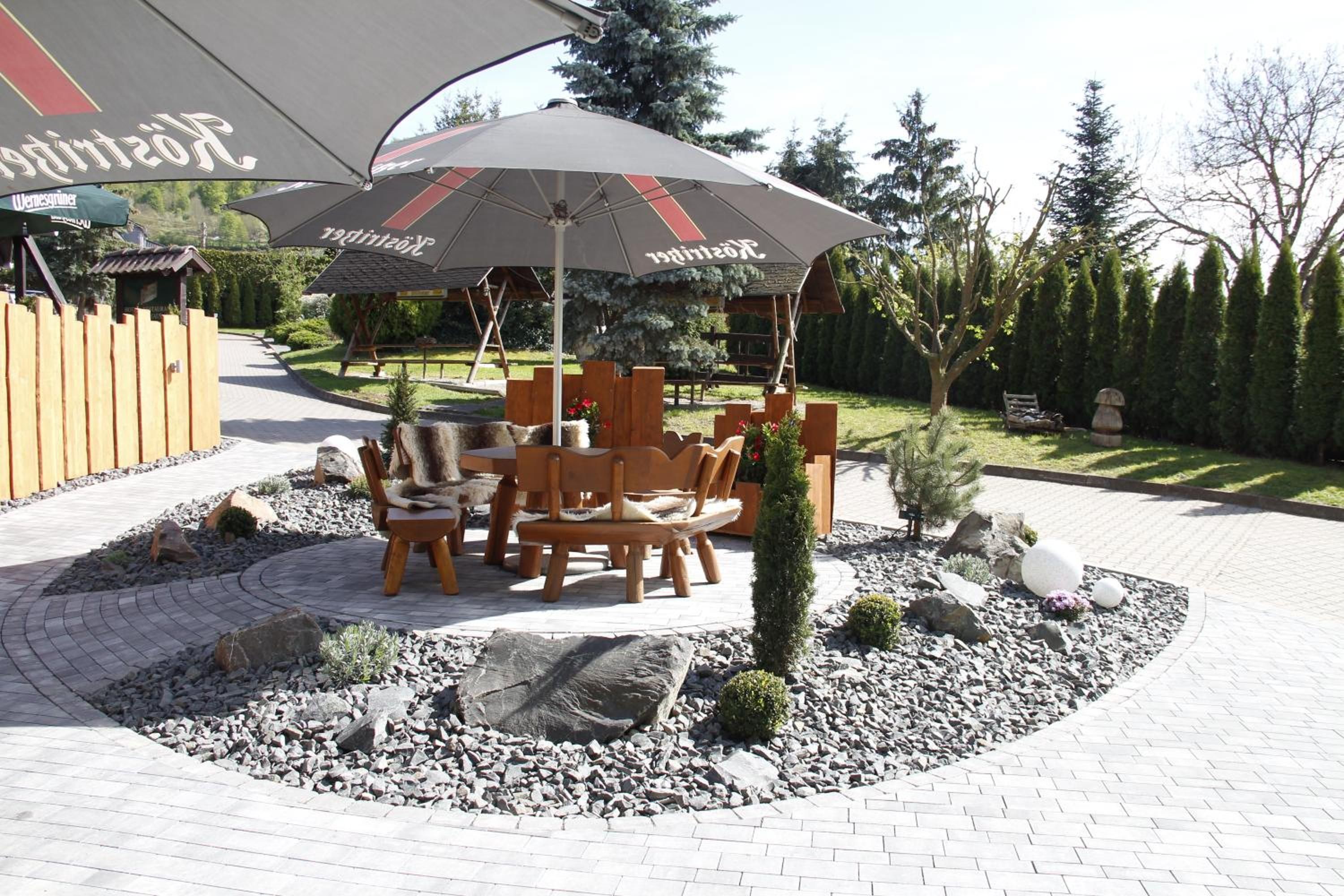 Un espacio al aire libre con mesa y sillas, un árbol pequeño y una composición decorativa de piedras.