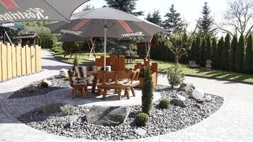 An outdoor seating area with a table and chairs, a small tree, and a decorative stone arrangement.