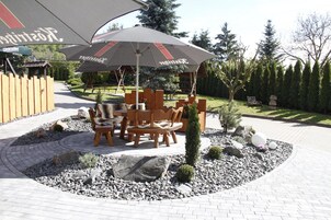 Un espacio al aire libre con mesa y sillas, un árbol pequeño y una composición decorativa de piedras.
