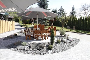 An outdoor seating area with a table and chairs, a small tree, and a decorative stone arrangement.