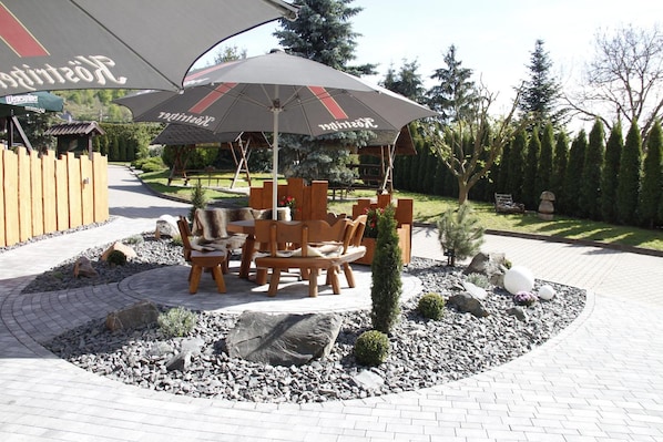 Un espacio al aire libre con mesa y sillas, un árbol pequeño y una composición decorativa de piedras.
