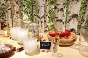 A breakfast buffet setup with various food items and utensils.
