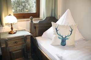 Un dormitorio con una cama de madera, una mesita de noche con una lámpara y una ventana con vistas a árboles.