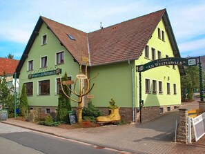 Un edificio tradicional con fachada verde, múltiples ventanas y un letrero que indica que es un hotel.
