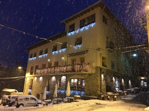 Ein Hotel mit Steinfassade, mehreren Balkonen und Außenbereichen mit Sitzgelegenheiten.