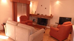 Una sala de estar con chimenea, un televisor y dos sofás.