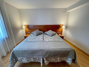 A single bed with a wooden headboard, two bedside tables, and a patterned bedspread.