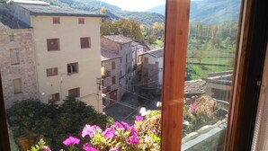 Vista de un edificio tradicional con numerosas ventanas y un balcón adornado con flores rosadas.