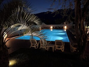 A swimming pool with lounge chairs and a palm tree. - Hotel Alesi (Malcesine)