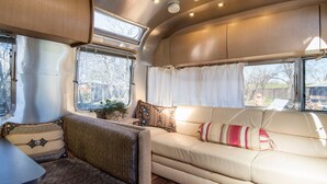 Ein gemütliches Wohnmobil-Interieur mit einer Sitzecke, einem kleinen Tisch und einem Fenster mit Vorhängen.
