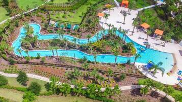 Relax by the resort's winding pool surrounded by lush greenery and palm trees.