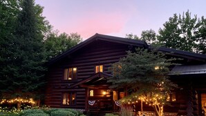 A log cabin with a stone foundation, a front porch, and a landscaped garden with various plants and a stone pathway. - Fully furnished log home in one of northern Wisconsin's last wilderness areas (Mercer)