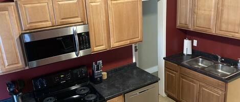 A kitchen with wooden cabinets, a stainless steel microwave, a stove, and a dishwasher.