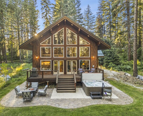 A log cabin with a deck, outdoor seating, and a hot tub.