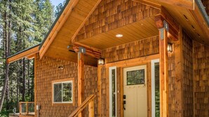 Une cabane en bois dotée d’une véranda, d’une porte d’entrée et d’un escalier menant à l’entrée.