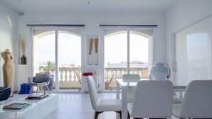 A modern living room with a dining area, large windows, and a view of the city. - Probably the best view In Malta (L-Isla)