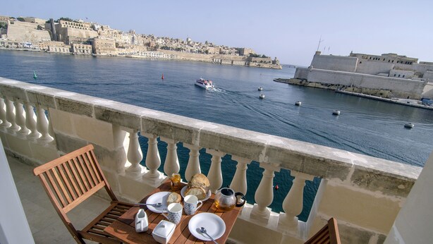 A balcony with a table set for breakfast overlooking a harbor with boats and a historic cityscape. - Probably the best view In Malta (L-Isla)
