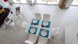 A dining area with a table set for four, white chairs, and a blue placemat. - Probably the best view In Malta (L-Isla)