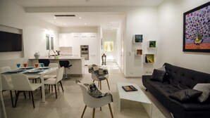 A modern living room with a black sofa, white dining table, and patterned chairs. - Probably the best view In Malta (L-Isla)