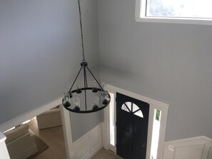 Stylish room with a striking black door, featuring a unique glass design, and a black chandelier.