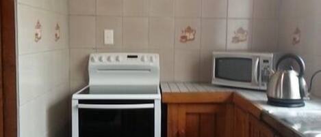 Eine kompakte Küche mit einem weißen Herd, einer Mikrowelle und Holzschränken.