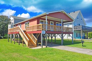 A two-story house with a wooden deck and a staircase leading to a second level.
