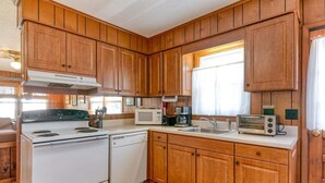 A kitchen with wooden cabinets, a stove, a microwave, a sink, and a toaster. - 401 Dog-Friendly - minutes to Beach Access & YMCA (Nags Head)
