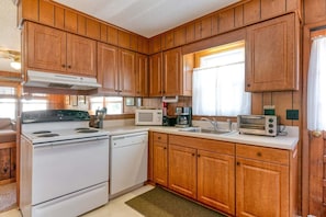 Une cuisine avec des meubles de rangement en bois, une cuisinière, un four à micro-ondes, un évier et un grille-pain.