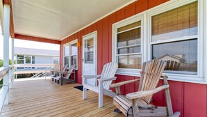 A wooden deck with Adirondack chairs and a rocking chair, a covered porch with a red exterior, and a white railing. - 401 Dog-Friendly - minutes to Beach Access & YMCA (Nags Head)