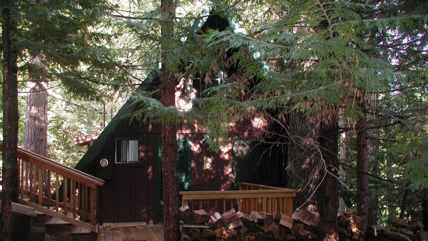 Una baita con veranda in legno, parete in pietra e scala che conduce all'ingresso.