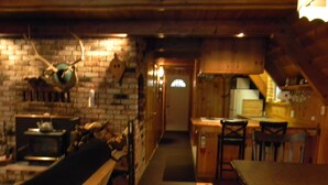 Un ambiente accogliente e rustico con una panca in legno, un camino e un angolo cottura con mobili e piano di lavoro in legno.