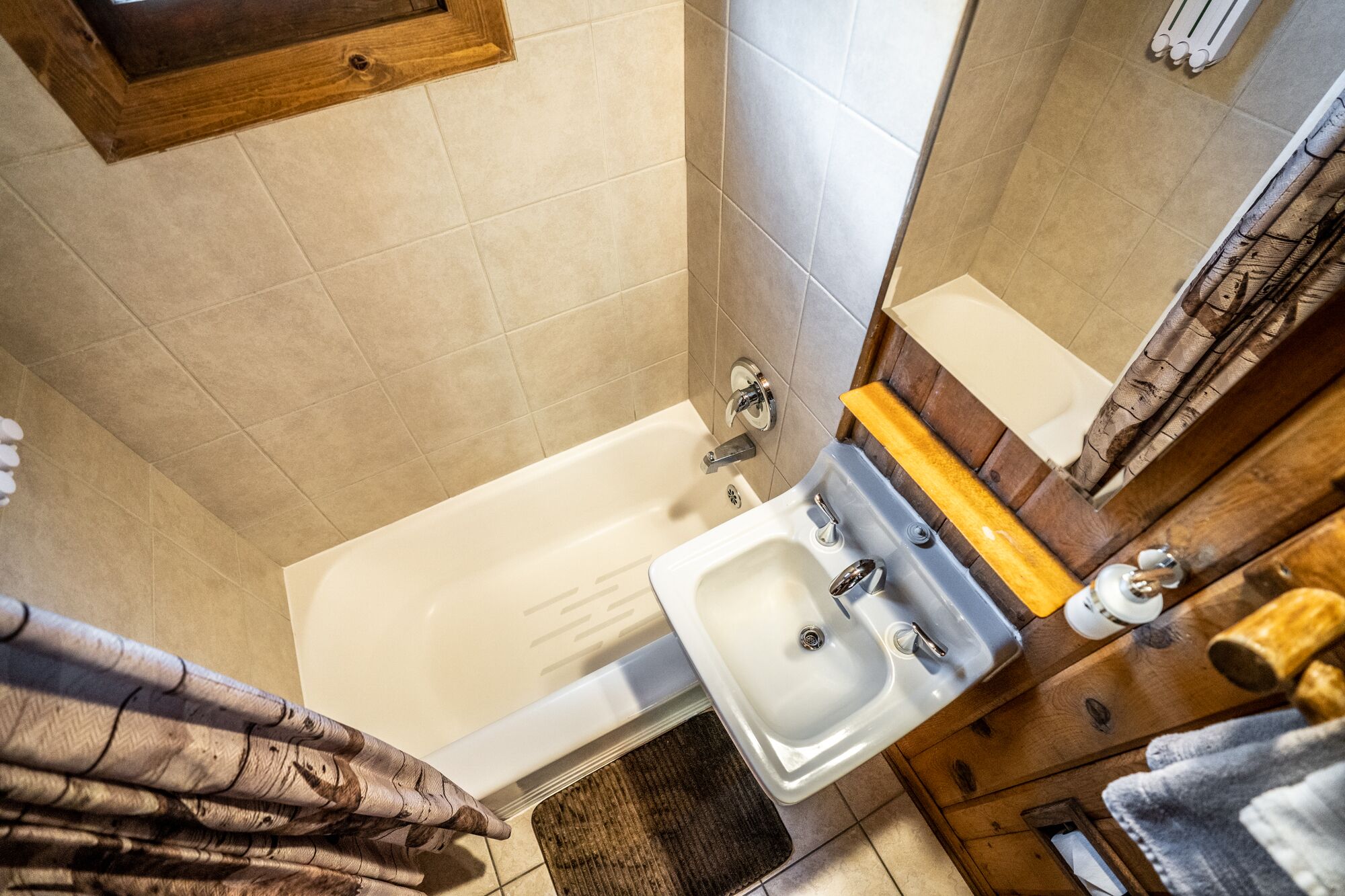 A bathroom with a bathtub, a sink, and a wooden vanity.