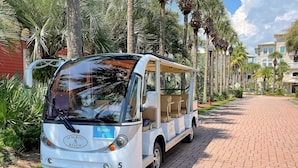 Een witte bus met een blauw routebordje met daarop 'Route E' geparkeerd op een met baksteen bestraat pad.