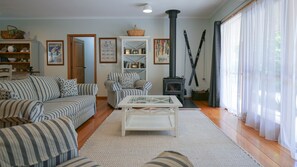 A cozy living room with striped sofas, a white coffee table, a bookshelf, and a fireplace.
