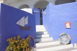 Un edificio blu con un murale raffigurante una barca a vela, una scala e piastrelle decorate.