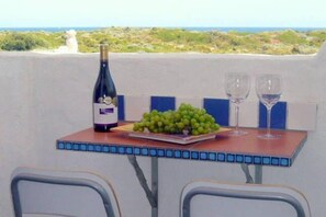 Un tavolo con una bottiglia di vino, un piatto di uva e due bicchieri, con vista panoramica.