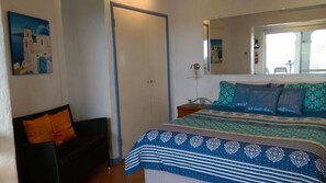 Una camera da letto con un letto, un comodino, una sedia e una porta.