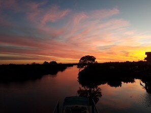 Tramonto su un fiume calmo, con una barca in primo piano.