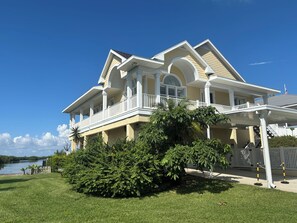 A two-story house with a balcony, a covered porch, and a view of a lake. - Stunning Key West Style Waterfront Home with Exceptional Views! (Tampa)