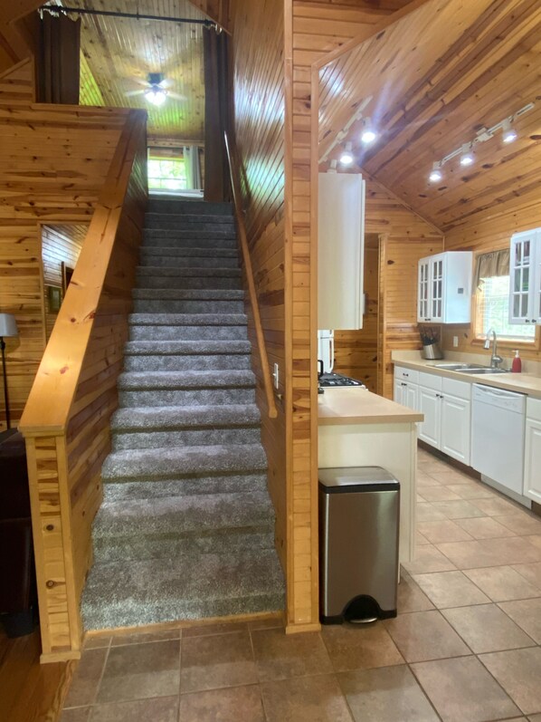 A wooden interior with a staircase leading to a kitchen area.