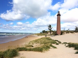A sandy beach with a lighthouse and grassy dunes. - Privacy and Luxury await! Fire Pit Patio, Large Outdoor Deck, and Heated Pool. (Mears)