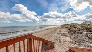 Een strand met een houten looppad dat naar een gebouw leidt.