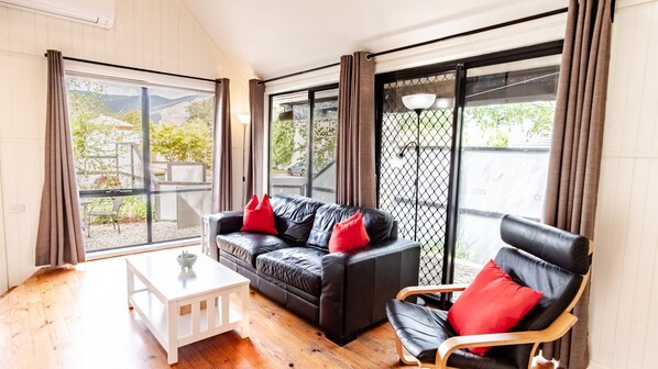 A room with a black leather sofa, a wooden chair, and a white coffee table.