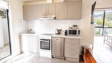A modern kitchen with white cabinets, a stainless steel stove, an oven, and a microwave.